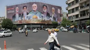 איראנים הולכים ליד שלט חוצות עם איורו של איסמעיל הנייה, טהרן, איראן, 11 במאי 2025
