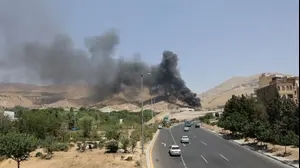 מכוניות חולפות על פני עשן המיתמר מטהראן, איראן, 16 ביוני 2025