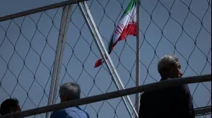 Afghan refugees in Iran stand under an Iranian flag on the Nature Bridge at a park during Sizdah Bedar, also known as Nature's Day, in the Abbasabad Cultural and Tourist Area in central Tehran, Iran, on April 2, 2025