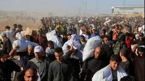 פלסטינים נושאים שקי מזון שחולקו במרכז של קרן הסיוע ההומניטרית בחאן יונס, רצועת עזה, 4 ביולי 2025