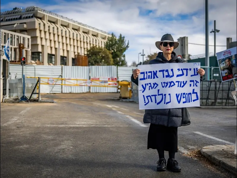 ורדה בן ברוך, סבתו של עידן אלכסנדר המוחזק בידי מחבלי חמאס ברצועת עזה, מחזיקה שלט בזמן שהיא עומדת מול משרד ראש הממשלה בירושלים, 23 בינואר 2025
